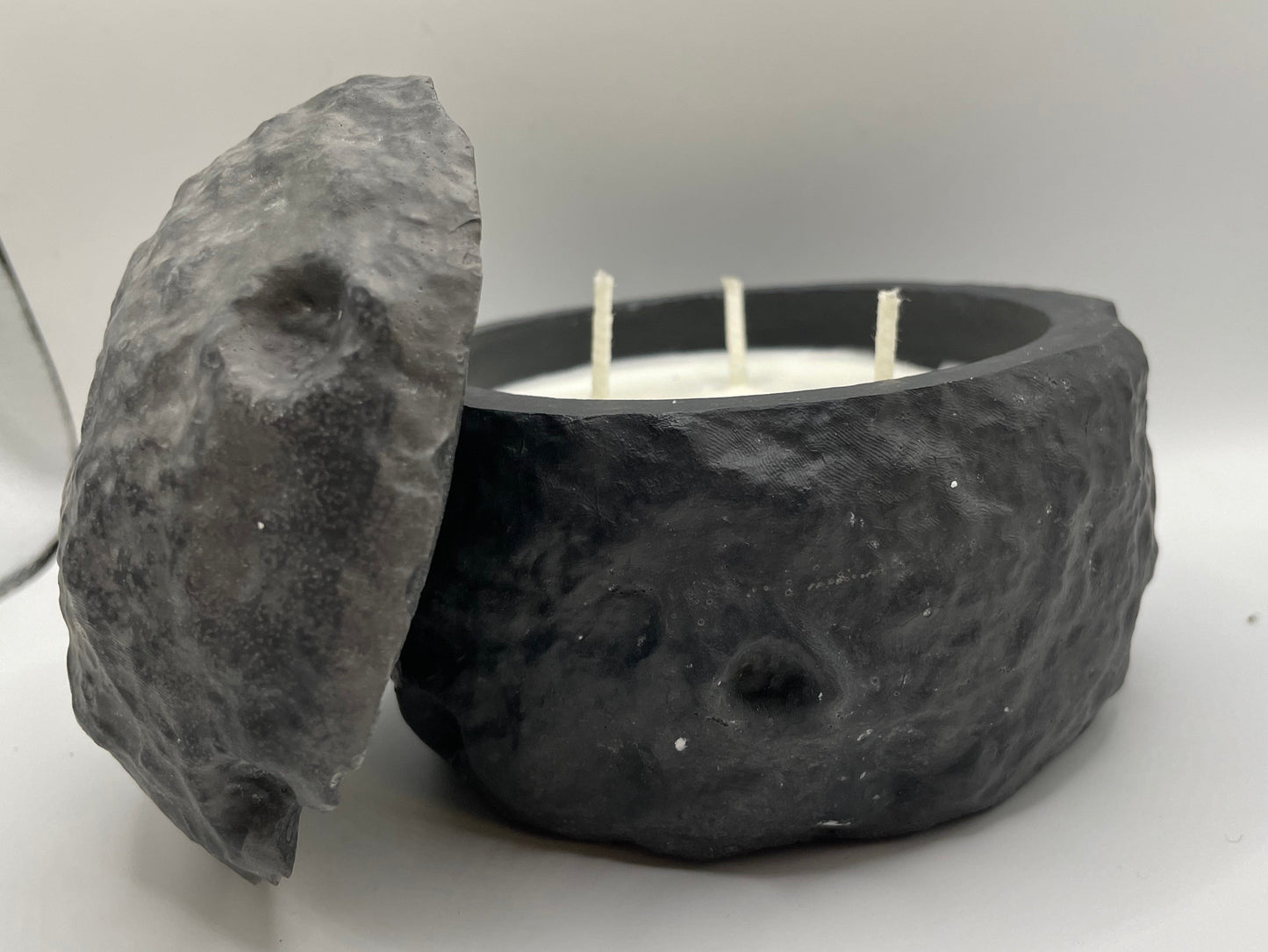 Candle in a stone holder with a stone lid on a white background