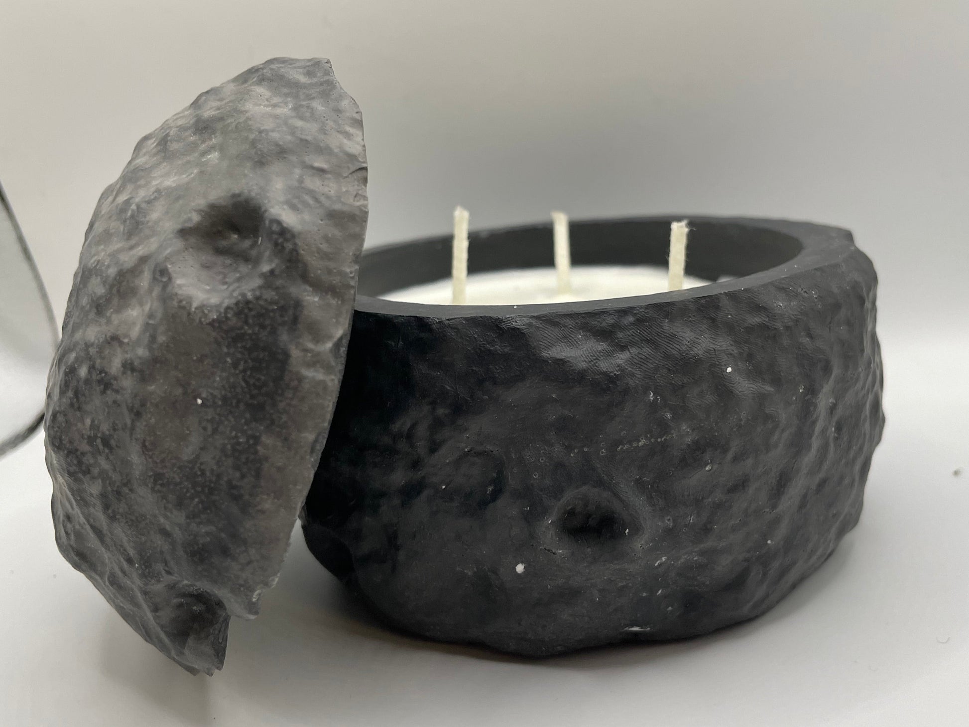 Candle in a stone holder with a stone lid on a white background