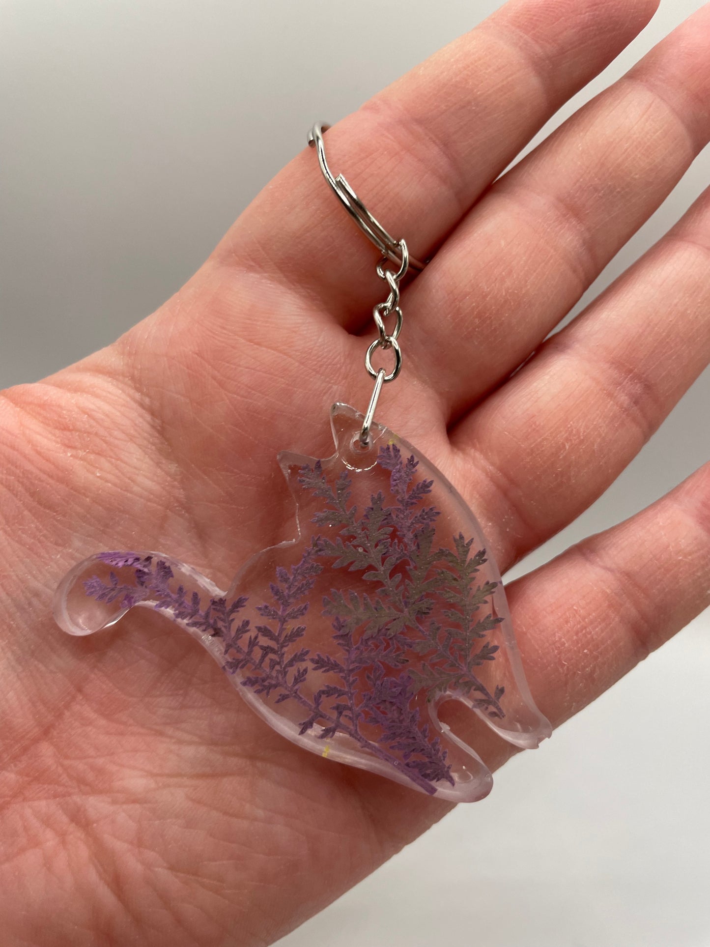 Hand holding a keychain with a purple and clear design