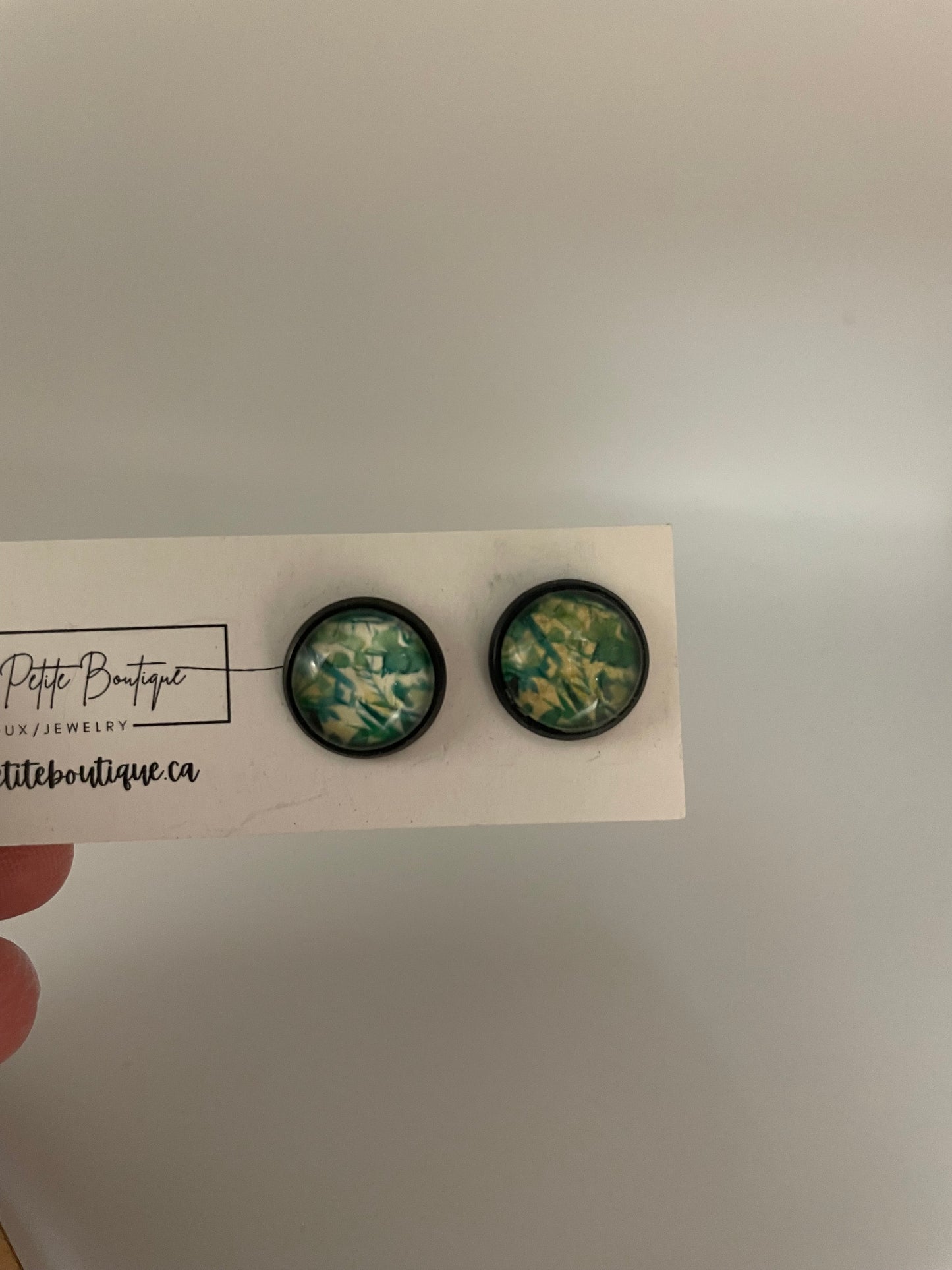 Two floral-patterned buttons on a card held by a hand with a neutral background