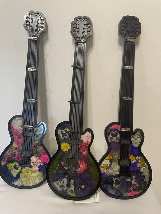 Three decorative guitars with floral patterns on a white background