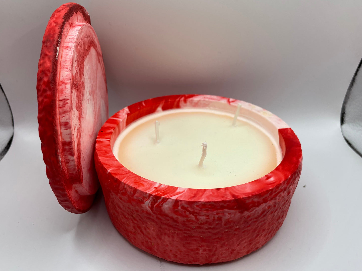 Red-wrapped candle with a white candle inside on a white surface