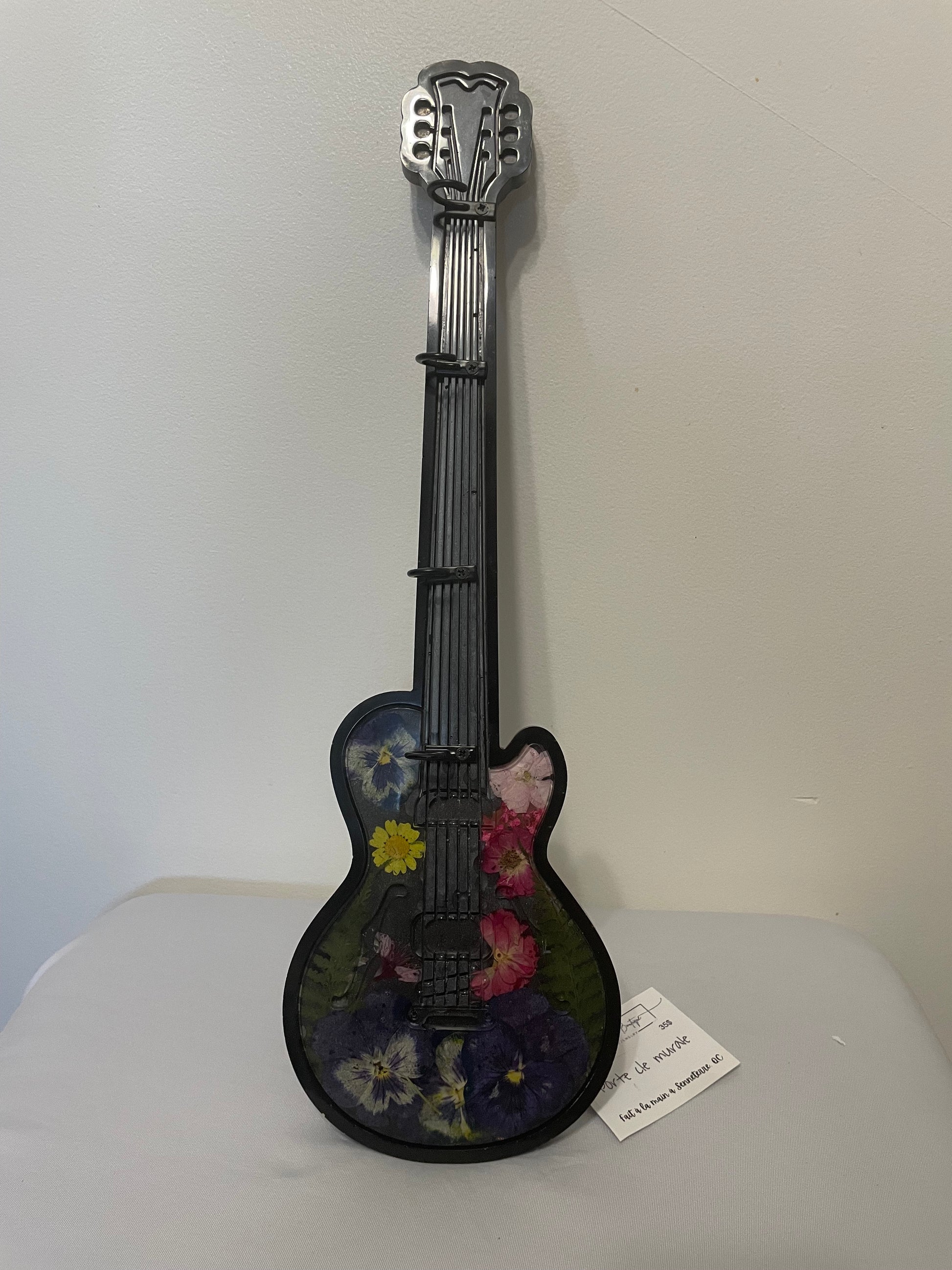 Decorative guitar-shaped object with floral design on a white surface