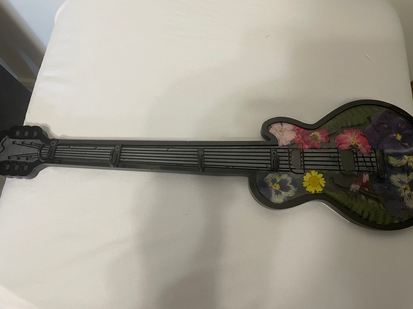 Small guitar-shaped object with floral designs on a white surface