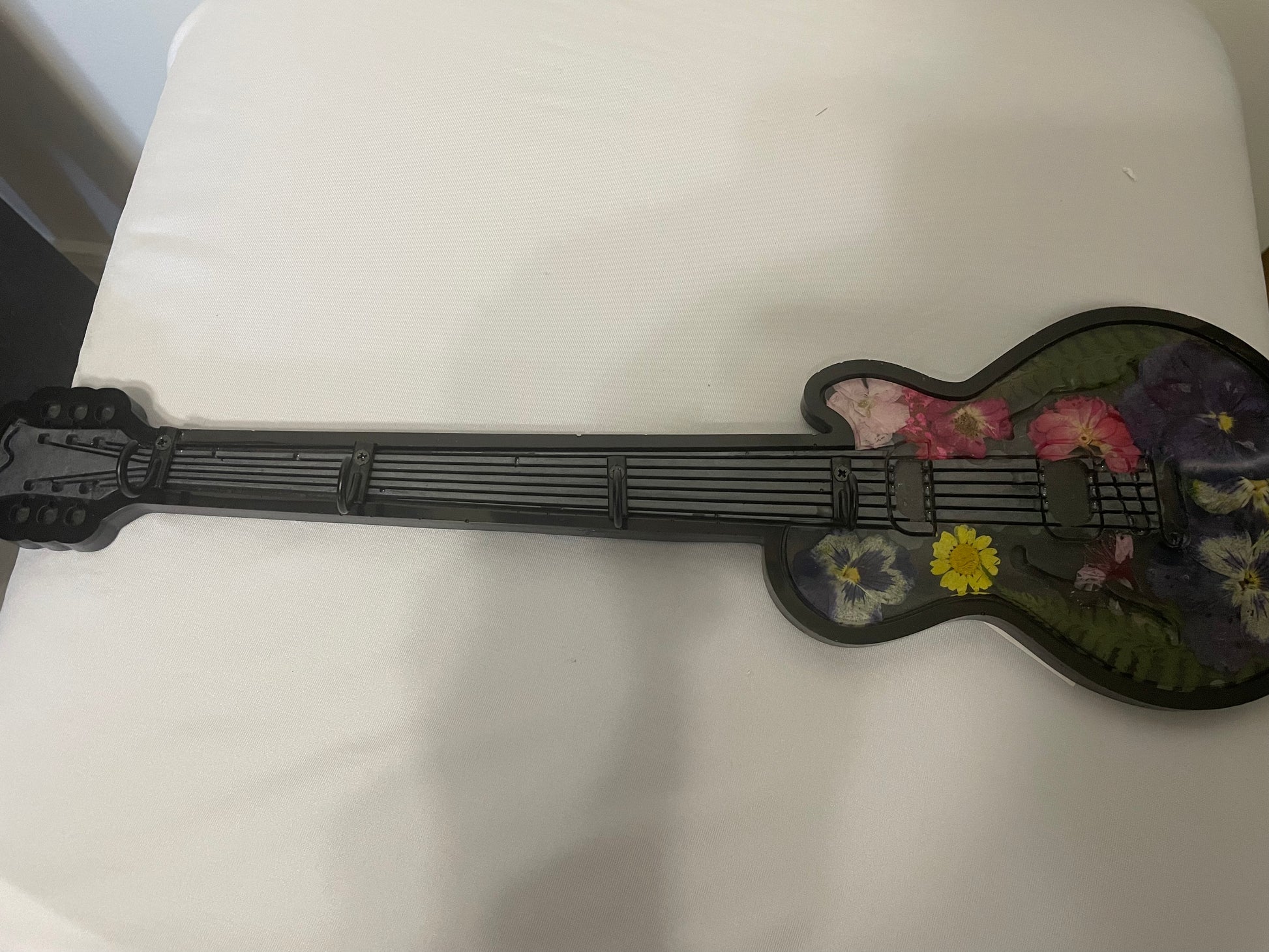 Small guitar-shaped object with floral designs on a white surface