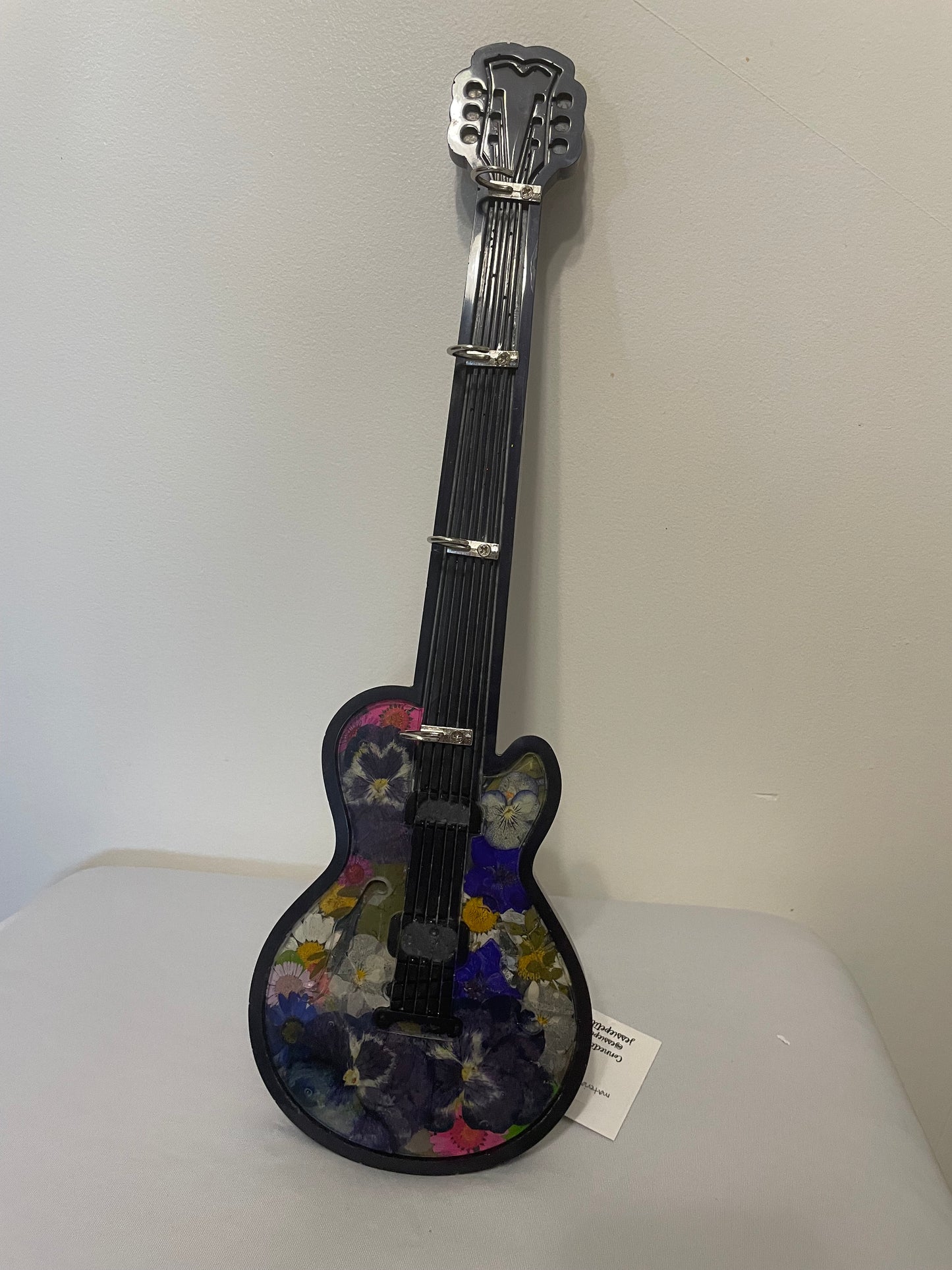 Decorative guitar with floral design on a white surface