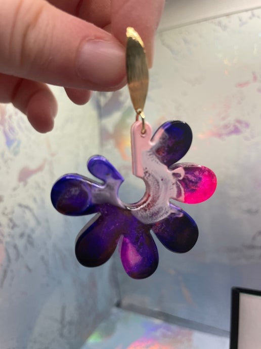 Colorful flower-shaped object held by a hand against a reflective surface
