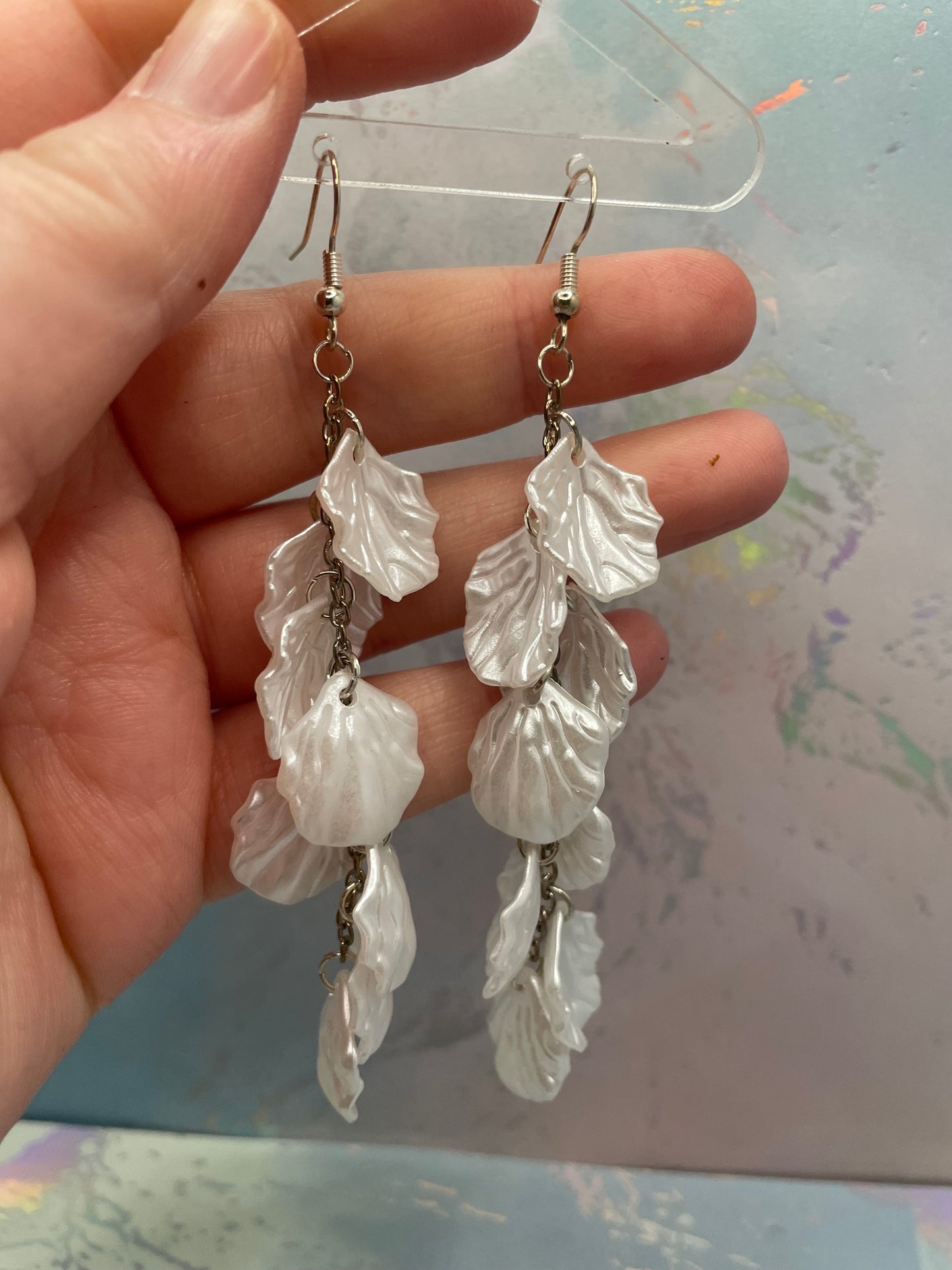 10.3cm-White Flower Petal Acrylic Dangle Earrings held in a hand against a blurred background