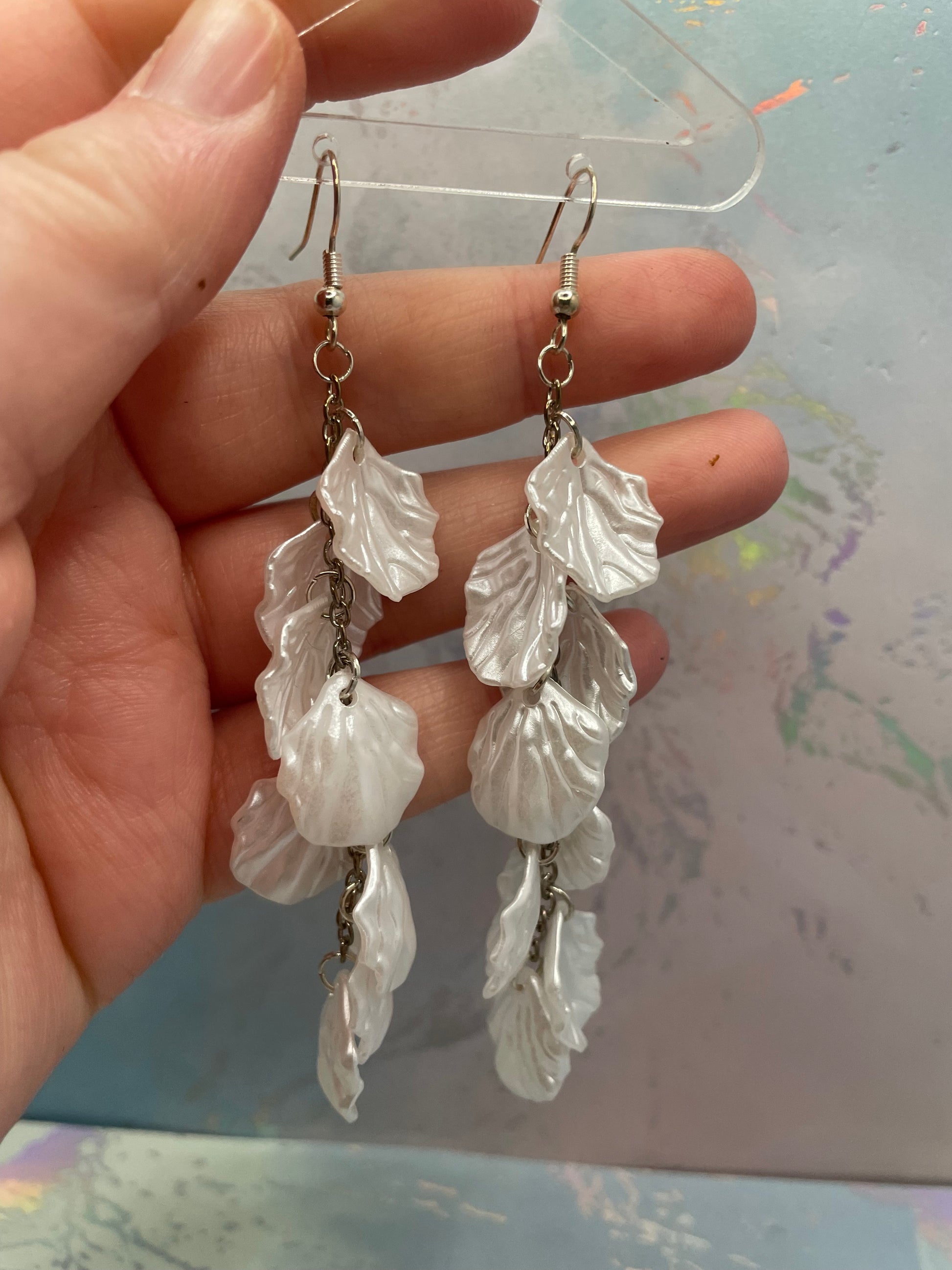 10.3cm-White Flower Petal Acrylic Dangle Earrings held in a hand against a blurred background
