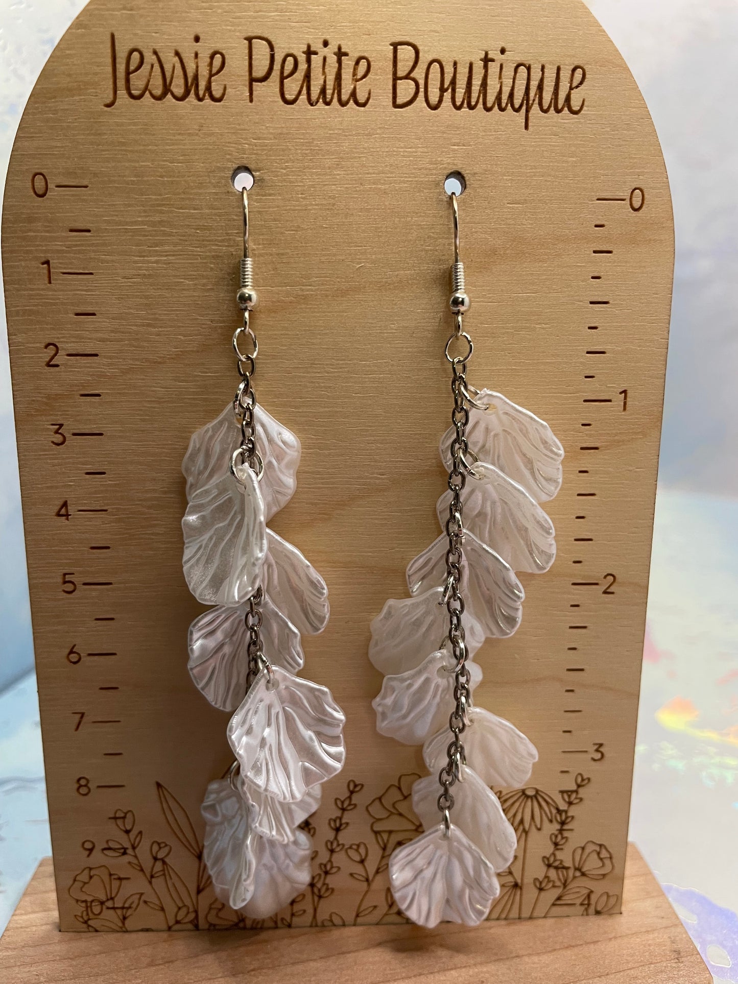 Leaf-shaped earrings on a wooden card with measurements, branded 'Jessie Petite Boutique'.