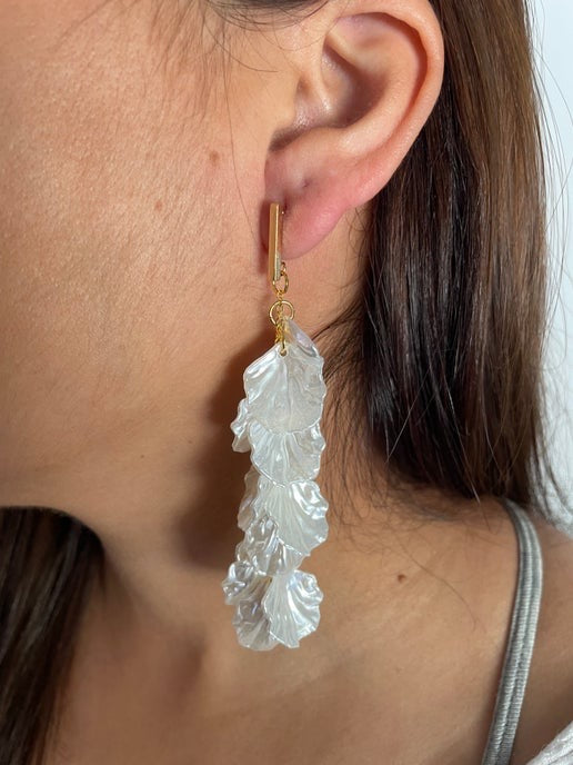 Close-up of a person wearing a pair of leaf-shaped earrings.