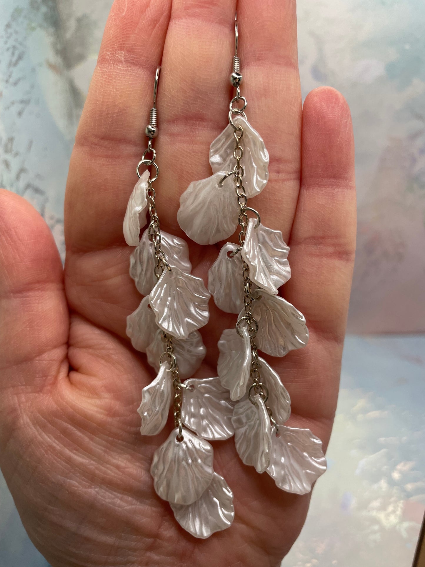 11cm-White Flower Petal Acrylic Dangle Earrings held in a hand against a light background