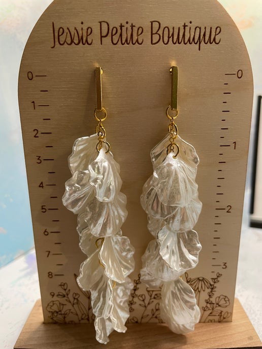 Pair of leaf-shaped earrings on a wooden display card with 'Jessie Petite Boutique' branding.