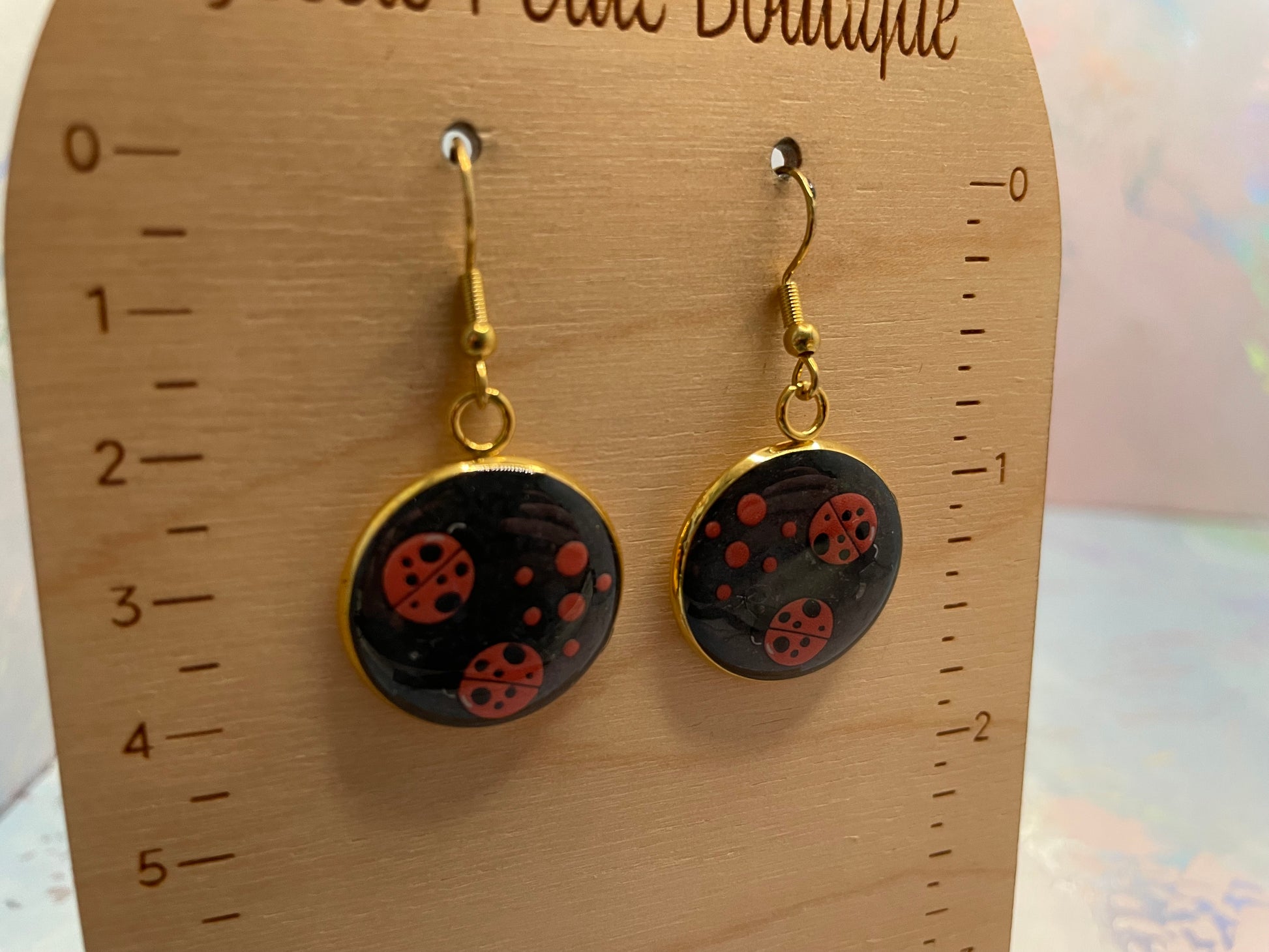 2Ladybug Round Earrings on a wooden display card.