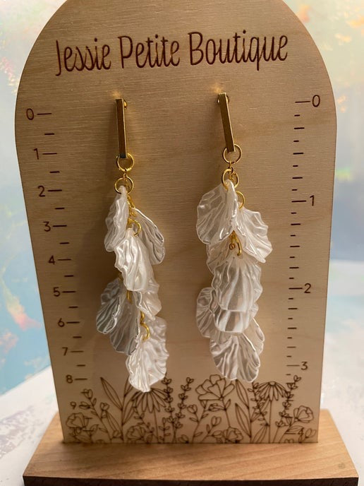 White leaf-shaped earrings on a wooden display card with 'Jessie Petite Boutique' branding.