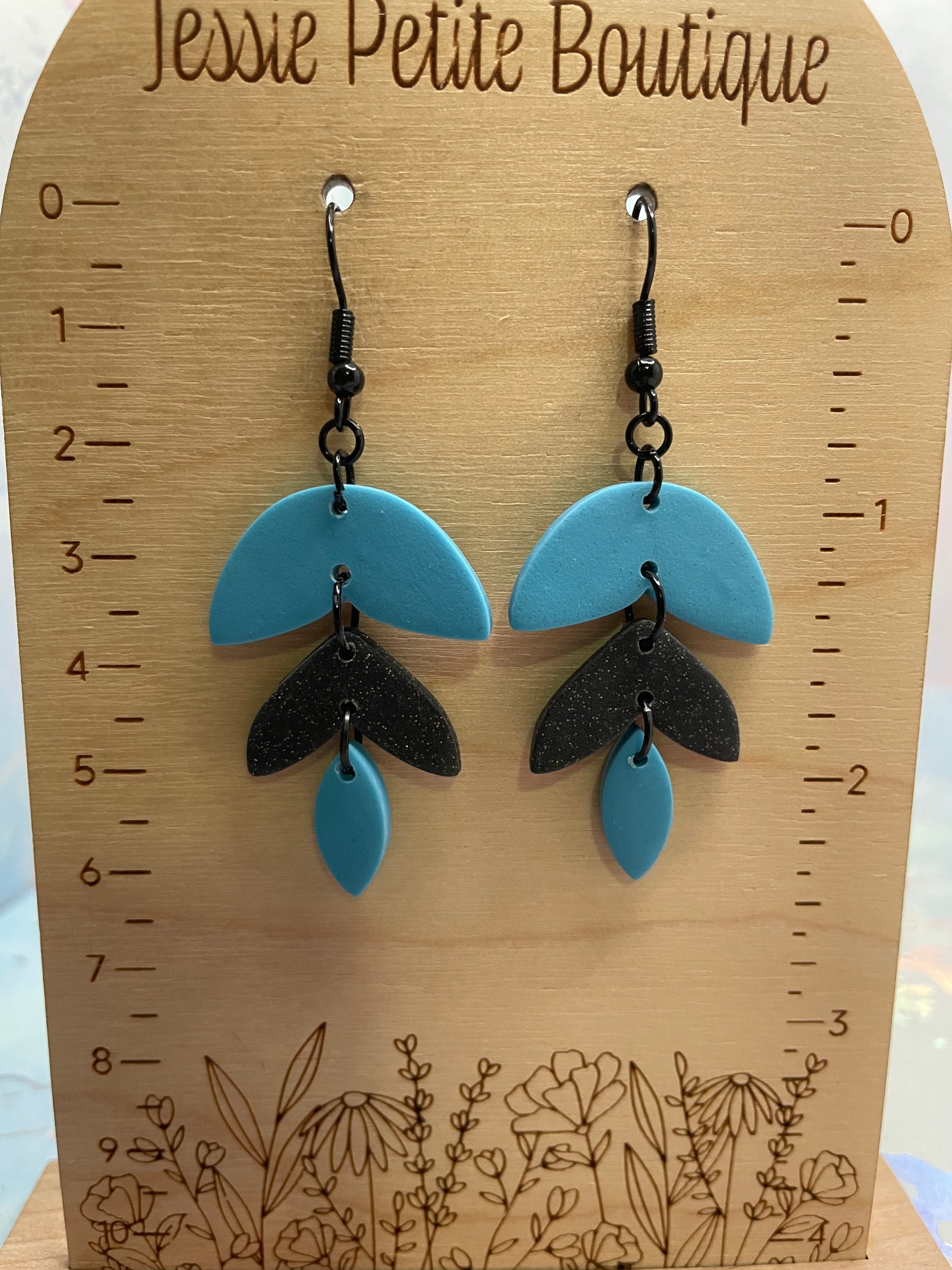 Pair of blue and black Alba earrings on a wooden board with measurements and 'Jessie Petite Boutique' branding.