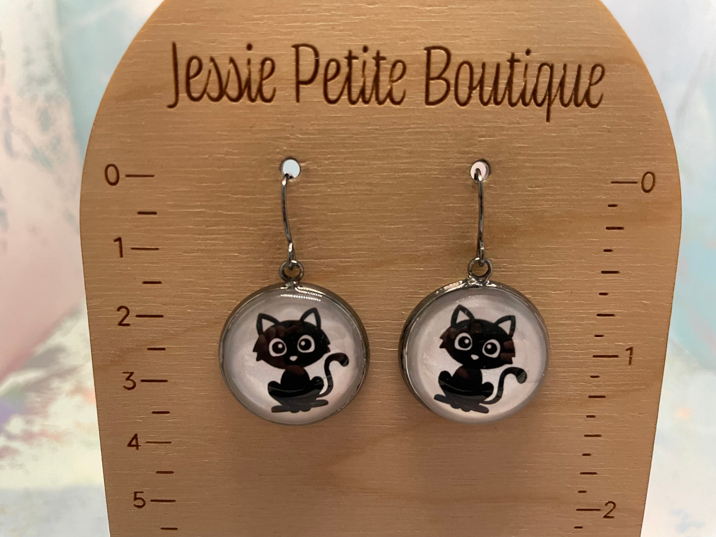 Cat-themed earrings on a wooden card with 'Jessie Petite Boutique' branding.