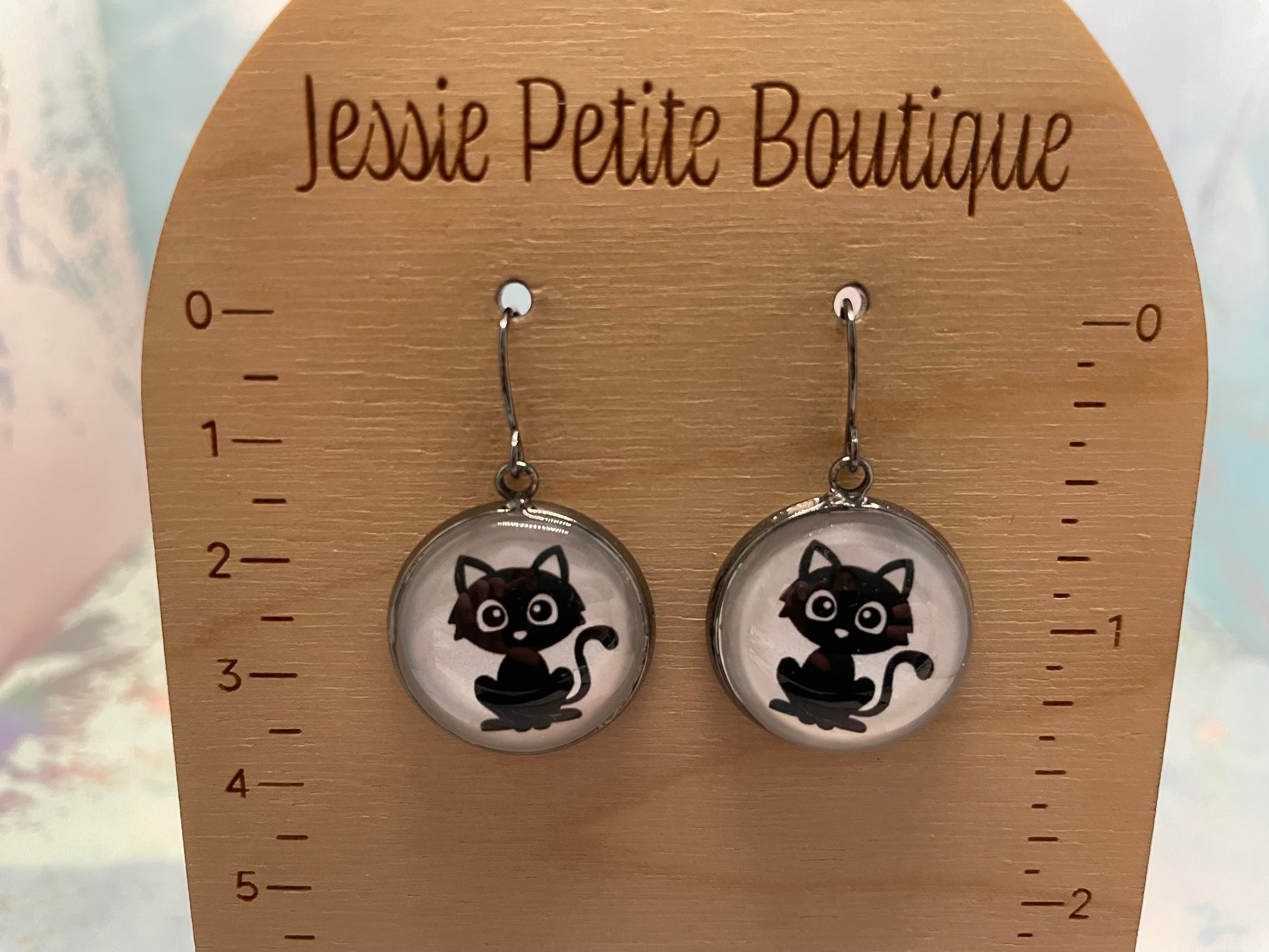 Cat-themed earrings on a wooden card with 'Jessie Petite Boutique' branding.