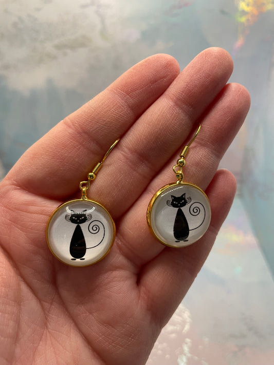 Black Cat Gold Cabochon Earrings held in a hand against a light background.