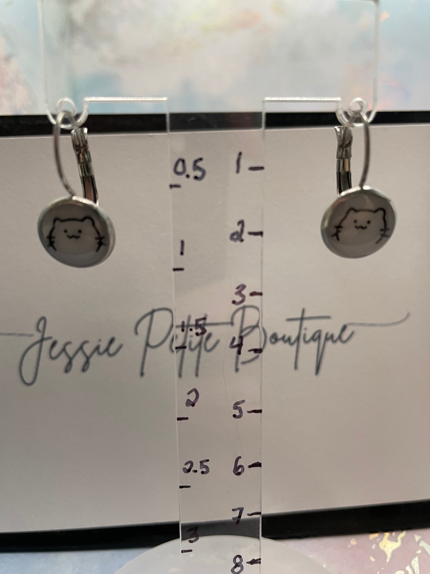 Cat Face Round Leverback Earrings on a measurement card labeled 'Jessie PETITE Boutique'.
