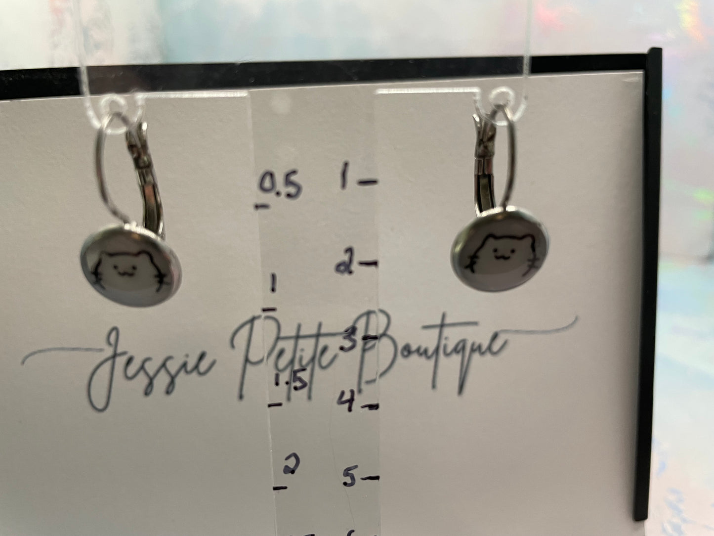 Silver earrings on a card with measurements and 'Jessie Petite Boutique' branding.