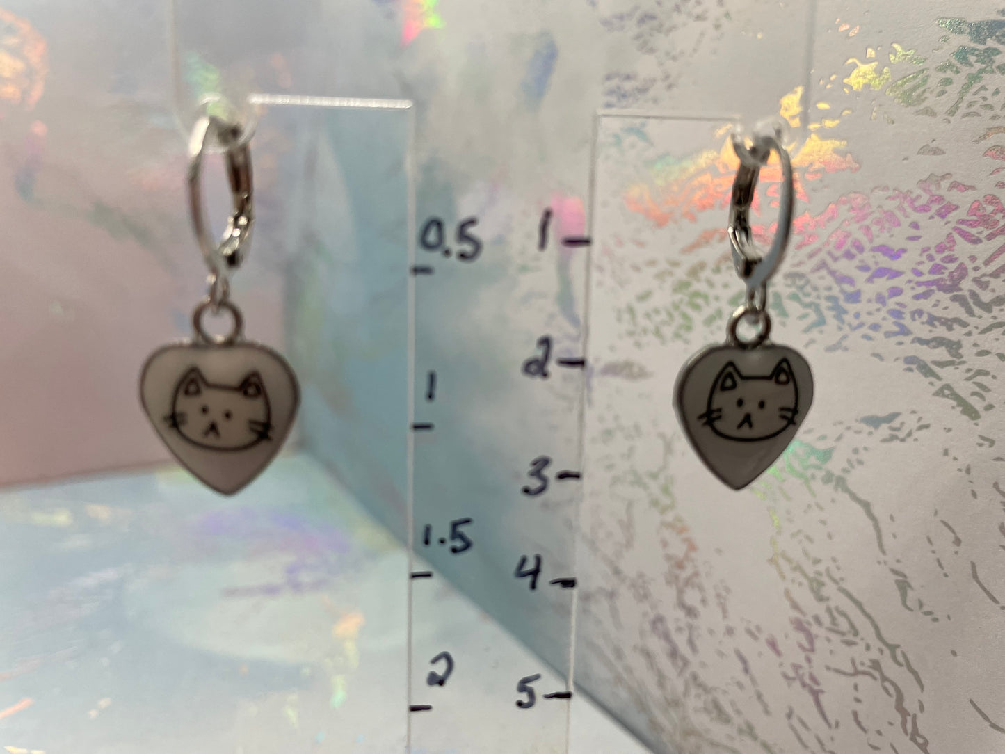 Heart-shaped charm with cat design on a clear ruler background