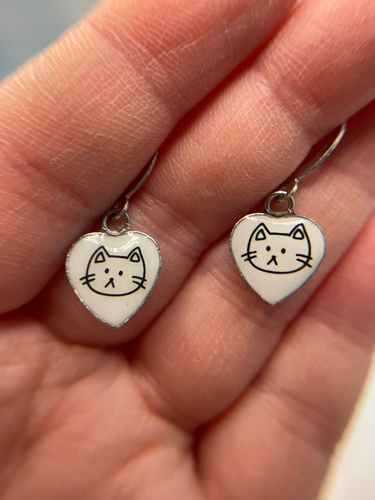 Heart-shaped earrings with cat faces held between fingers