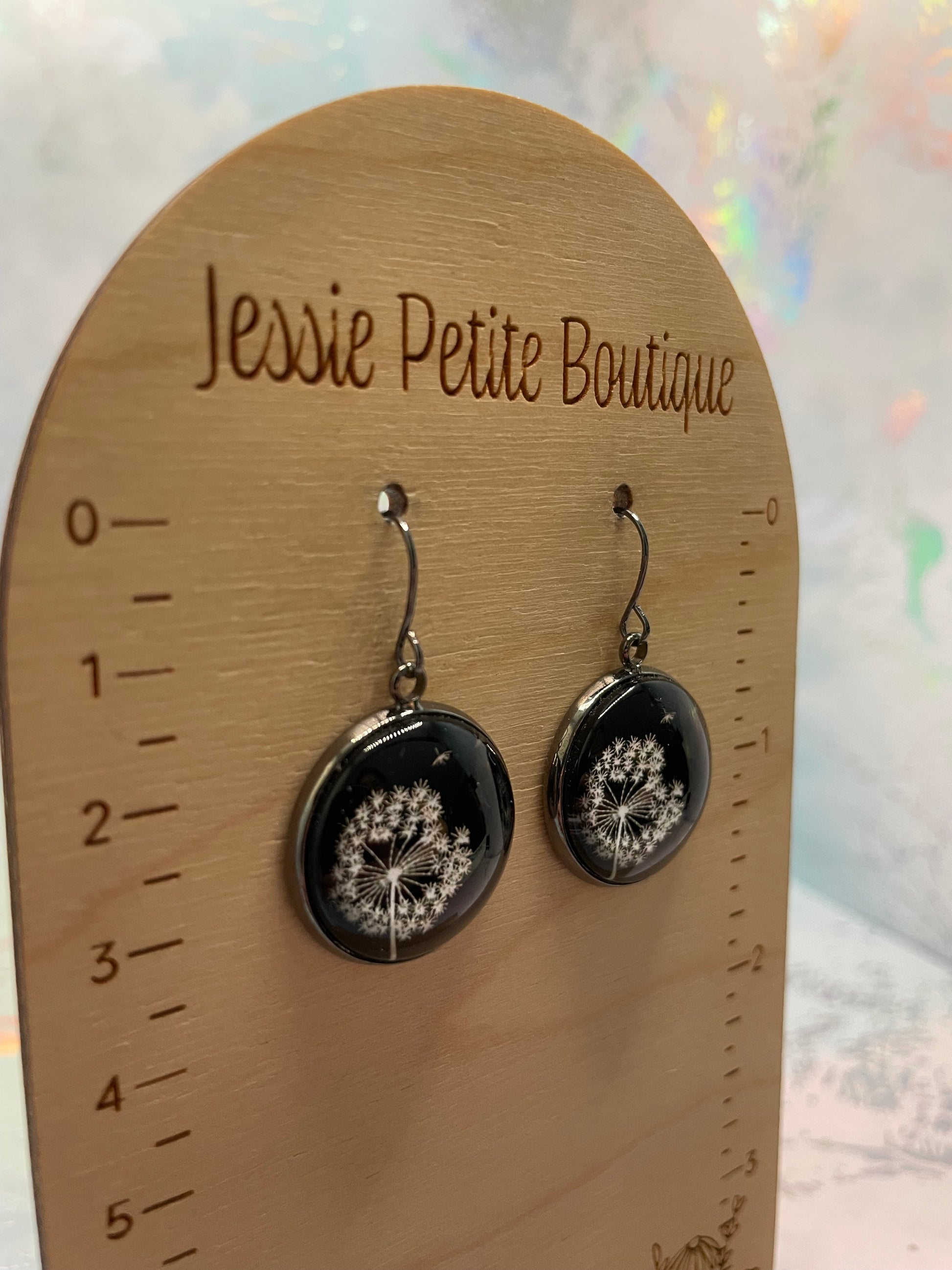 Black earrings with floral designs on a wooden card with 'Jessie Petite Boutique' branding.