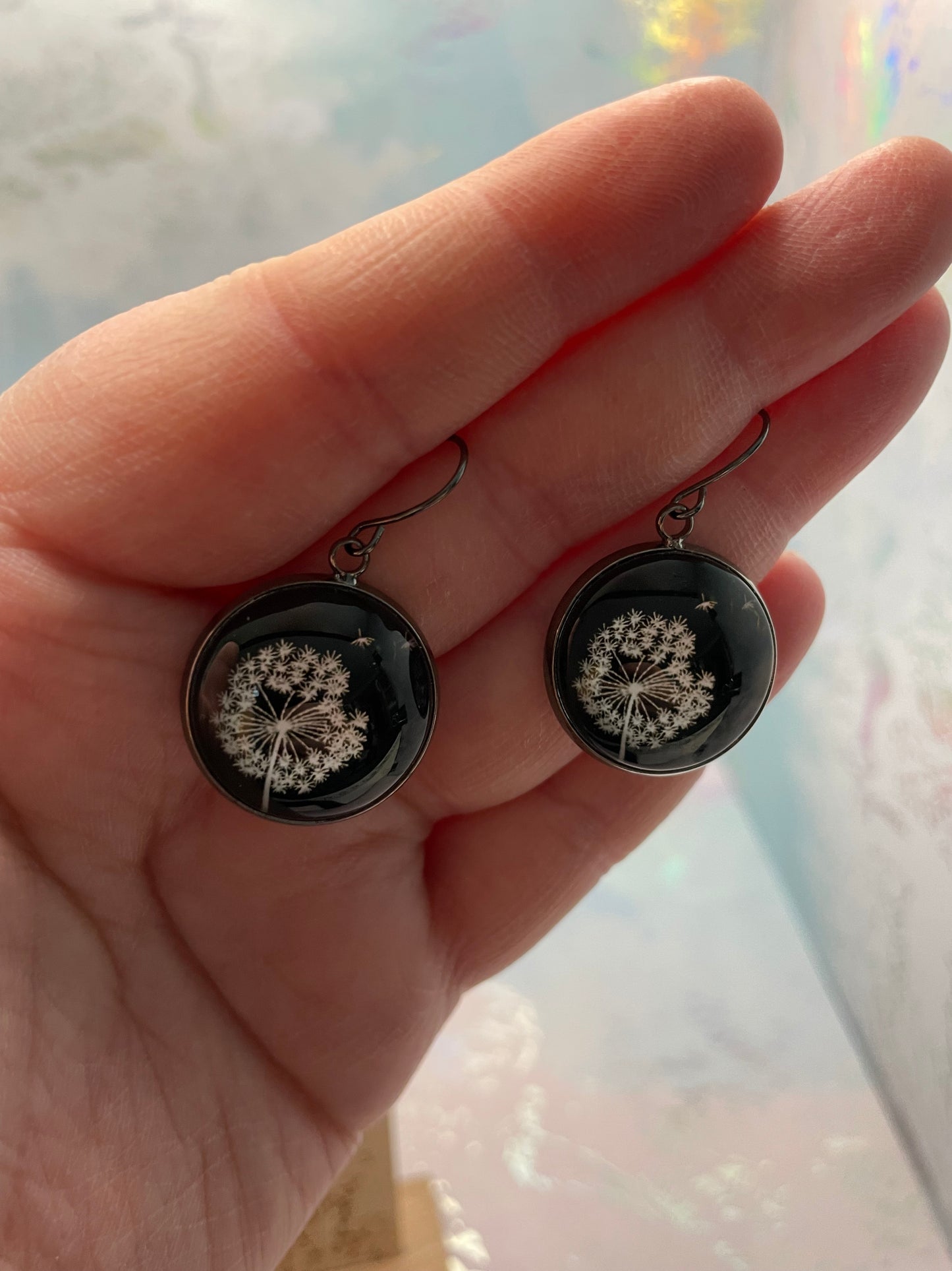 Dandelion Round Cabochon Earrings held in a hand against a blurred background