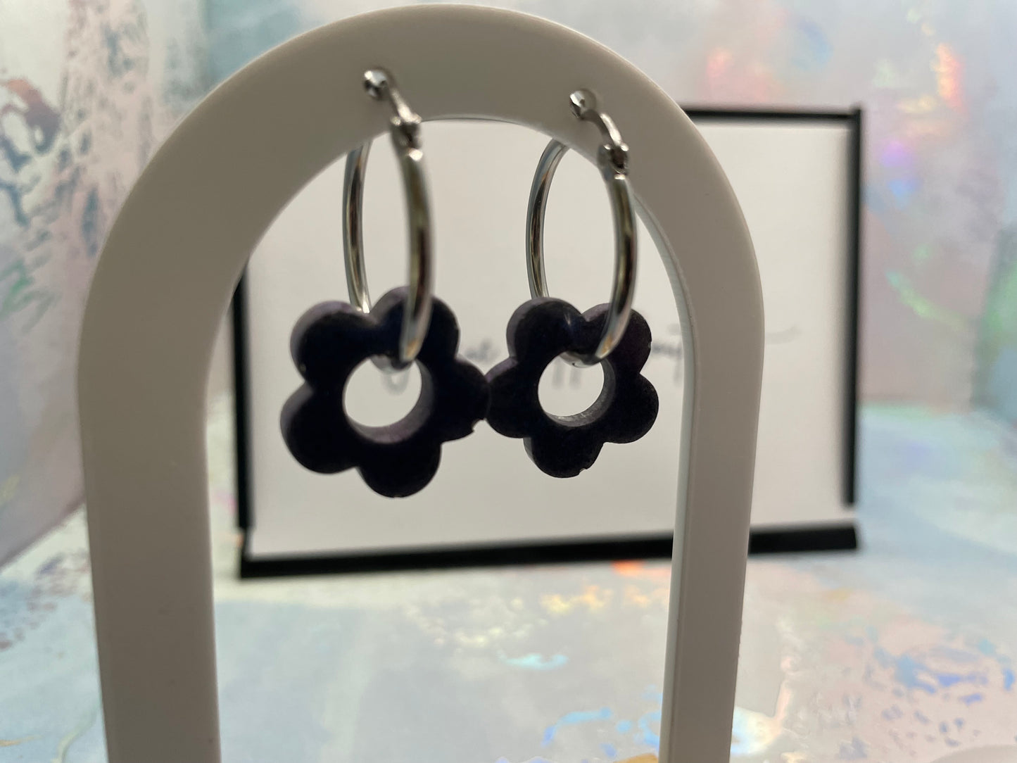 BLUE flower-shaped earrings on a white stand with a blurred background