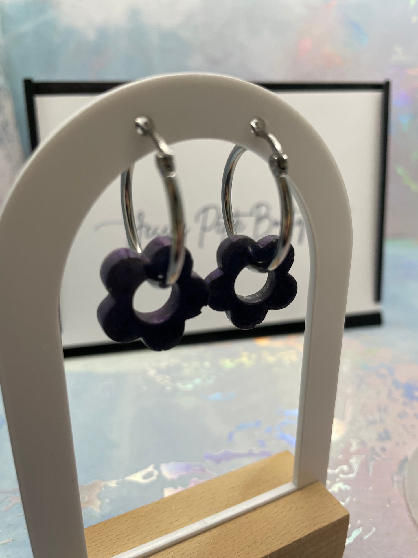 BLUEflower-shaped earrings on a white stand with a blurred background