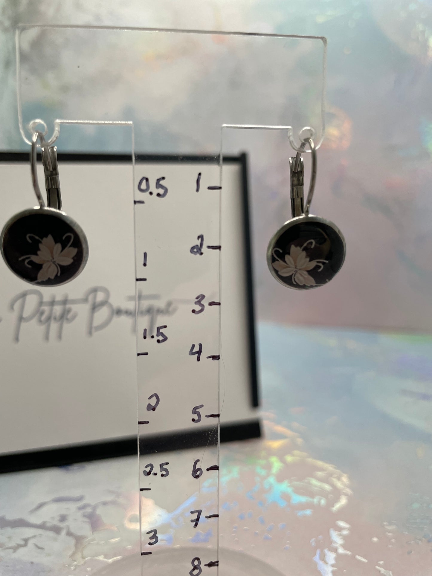 Mini Floral on Black EARRINGS on a clear stand with measurement scale.