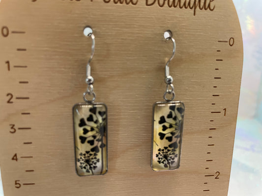 Pair of earrings with floral design on a wooden display card with measurements.
