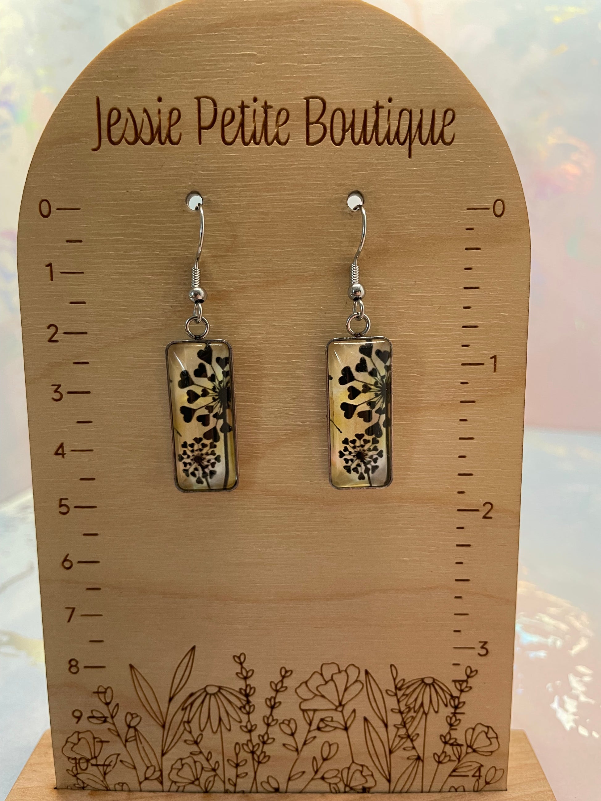 Pair of floral earrings on a wooden card with 'Jessie Petite Boutique' branding.