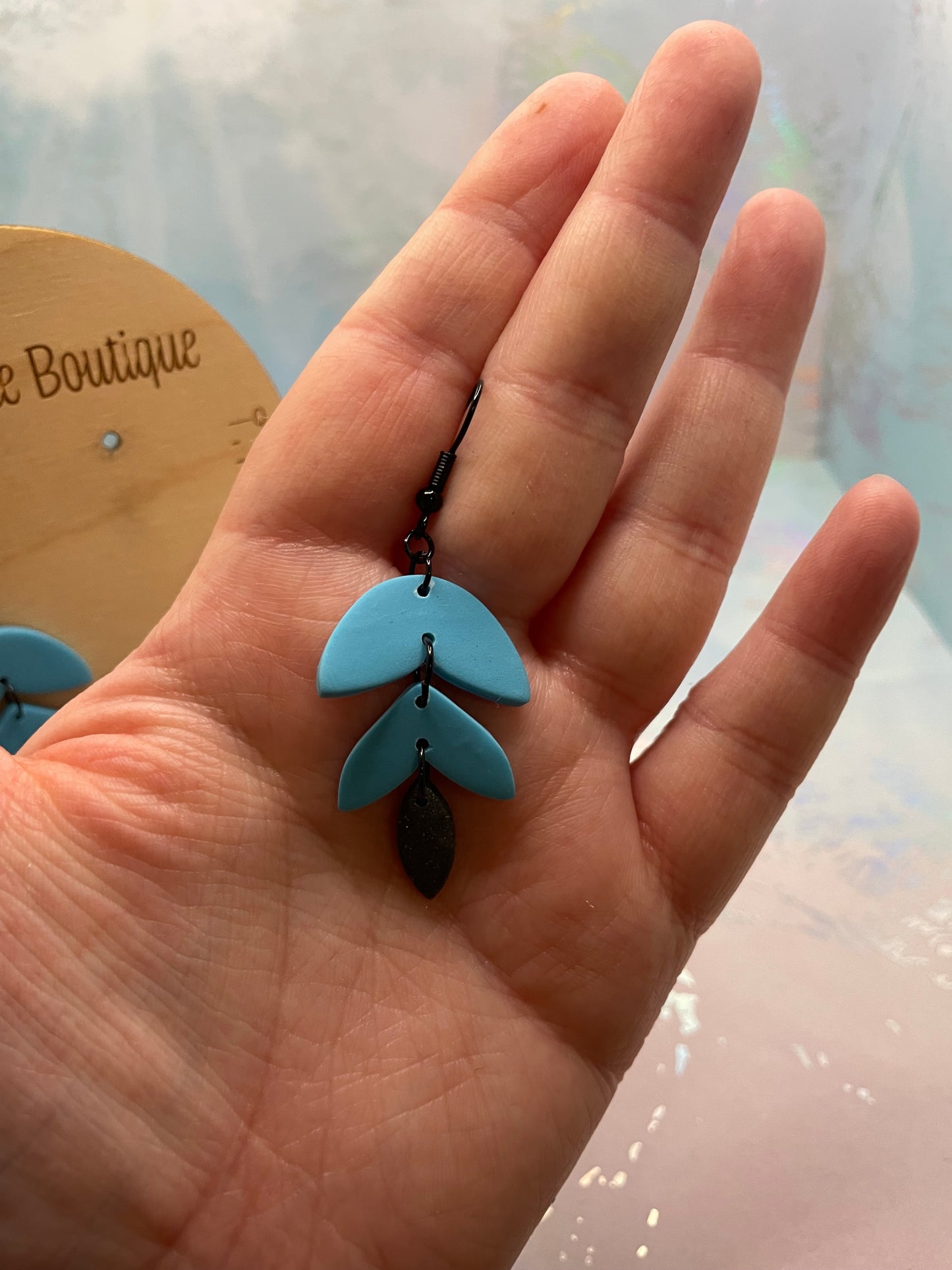 Hand holding a pair of blue earrings with a blurred background