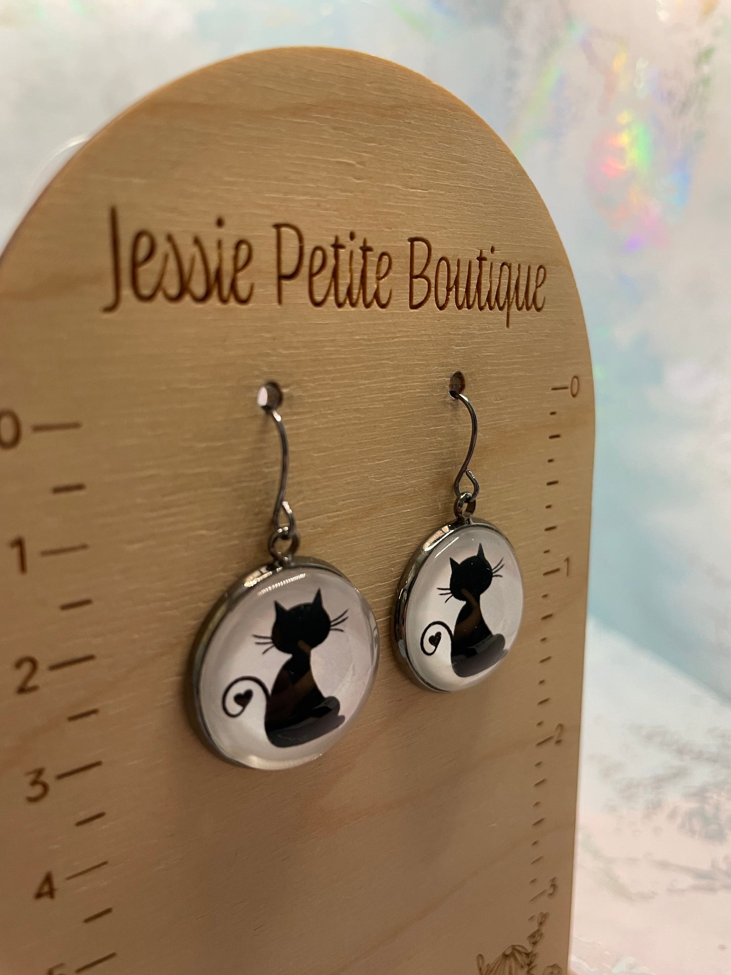 Cat-shaped earrings on a wooden card with 'Jessie Petite Boutique' branding.