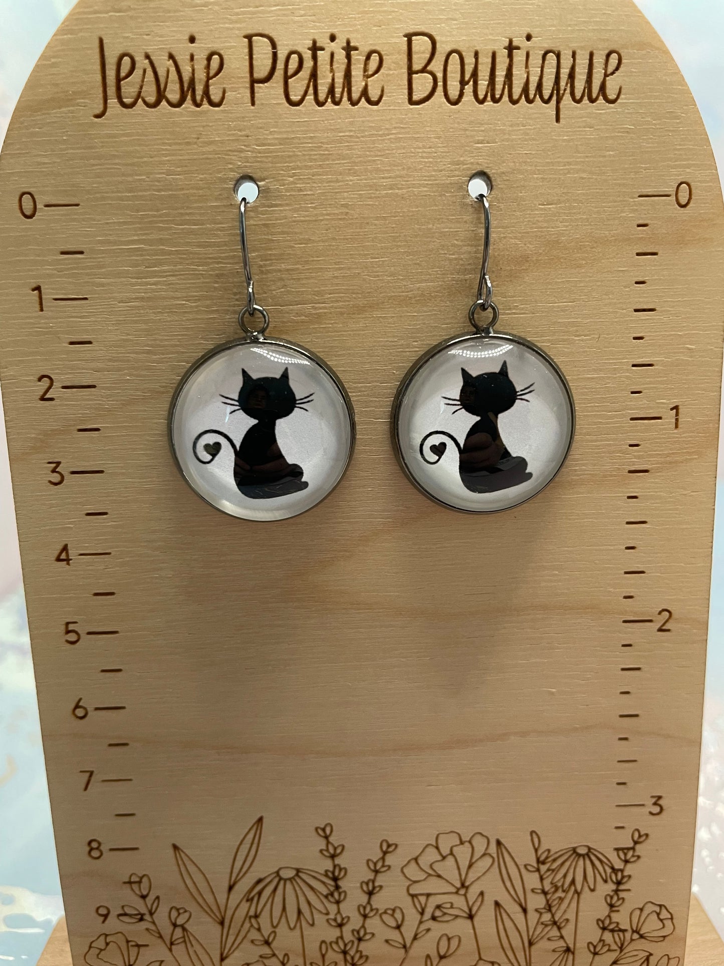 Cat-shaped earrings on a wooden card with floral designs and 'Jessie Petite Boutique' branding.