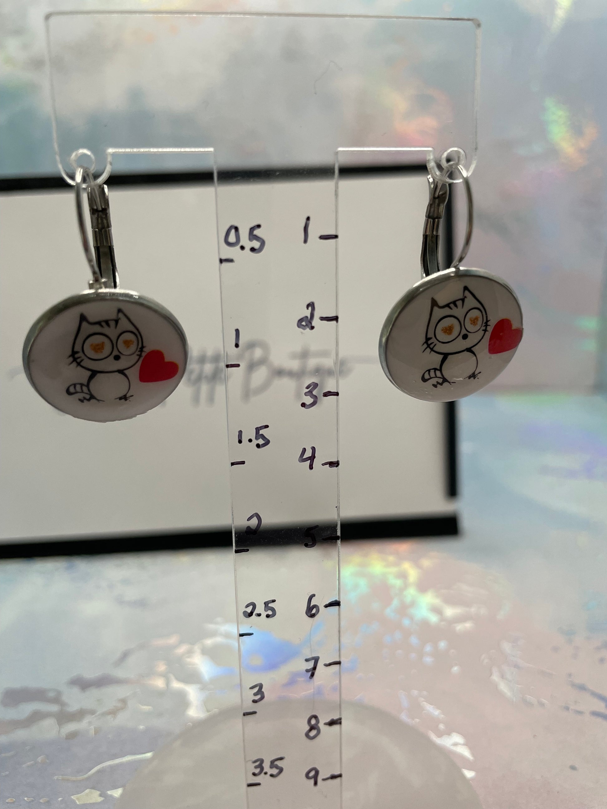 Cat-Themed Round Bezel Earrings on a clear ruler background