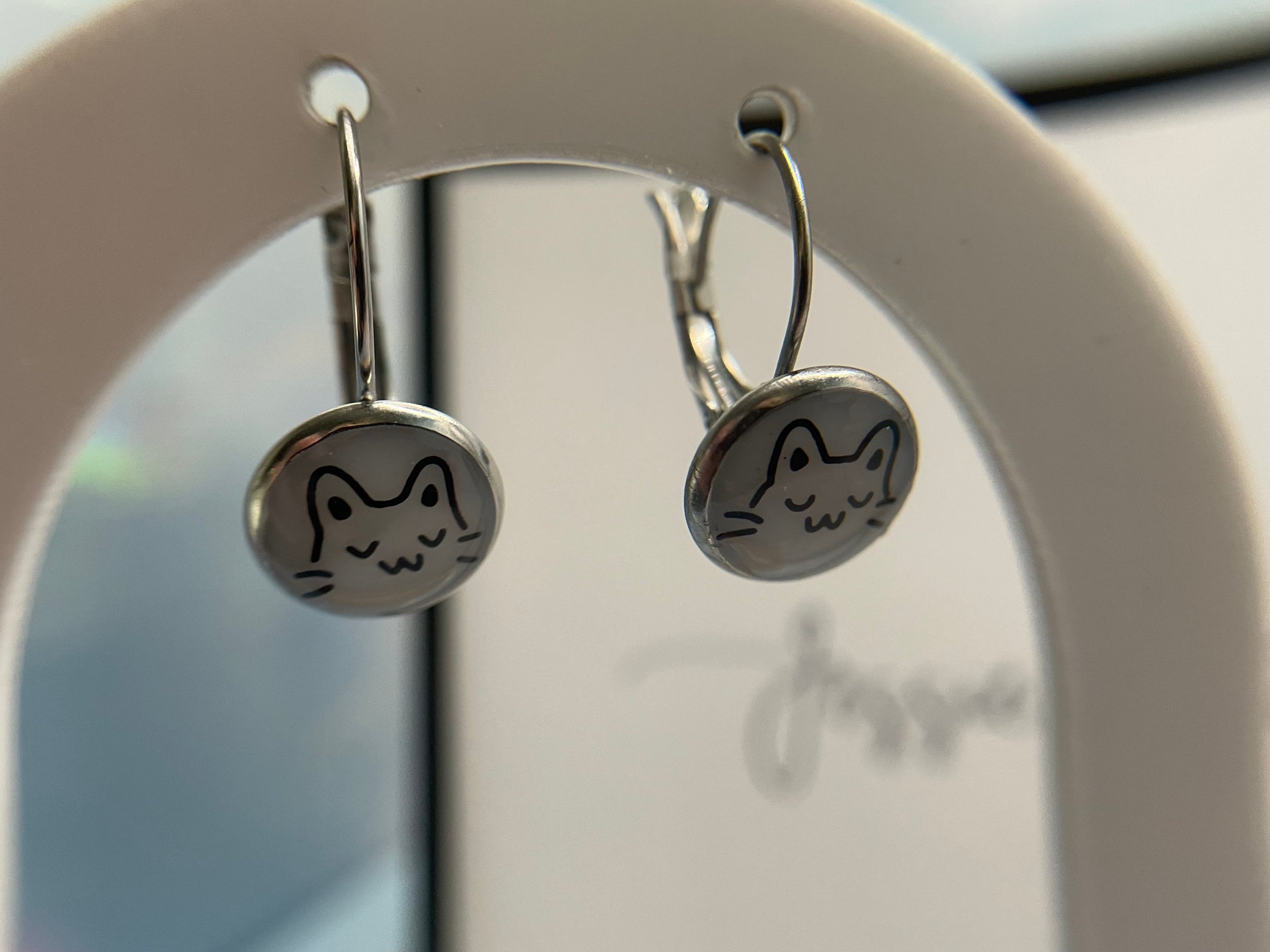 Cat-shaped earrings on a branded stand