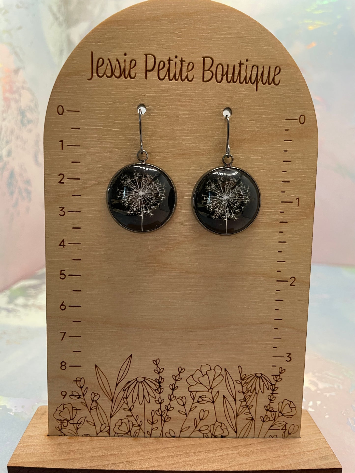 Pair of black earrings on a wooden display card with floral design and 'Jewel Petite Boutique' branding.