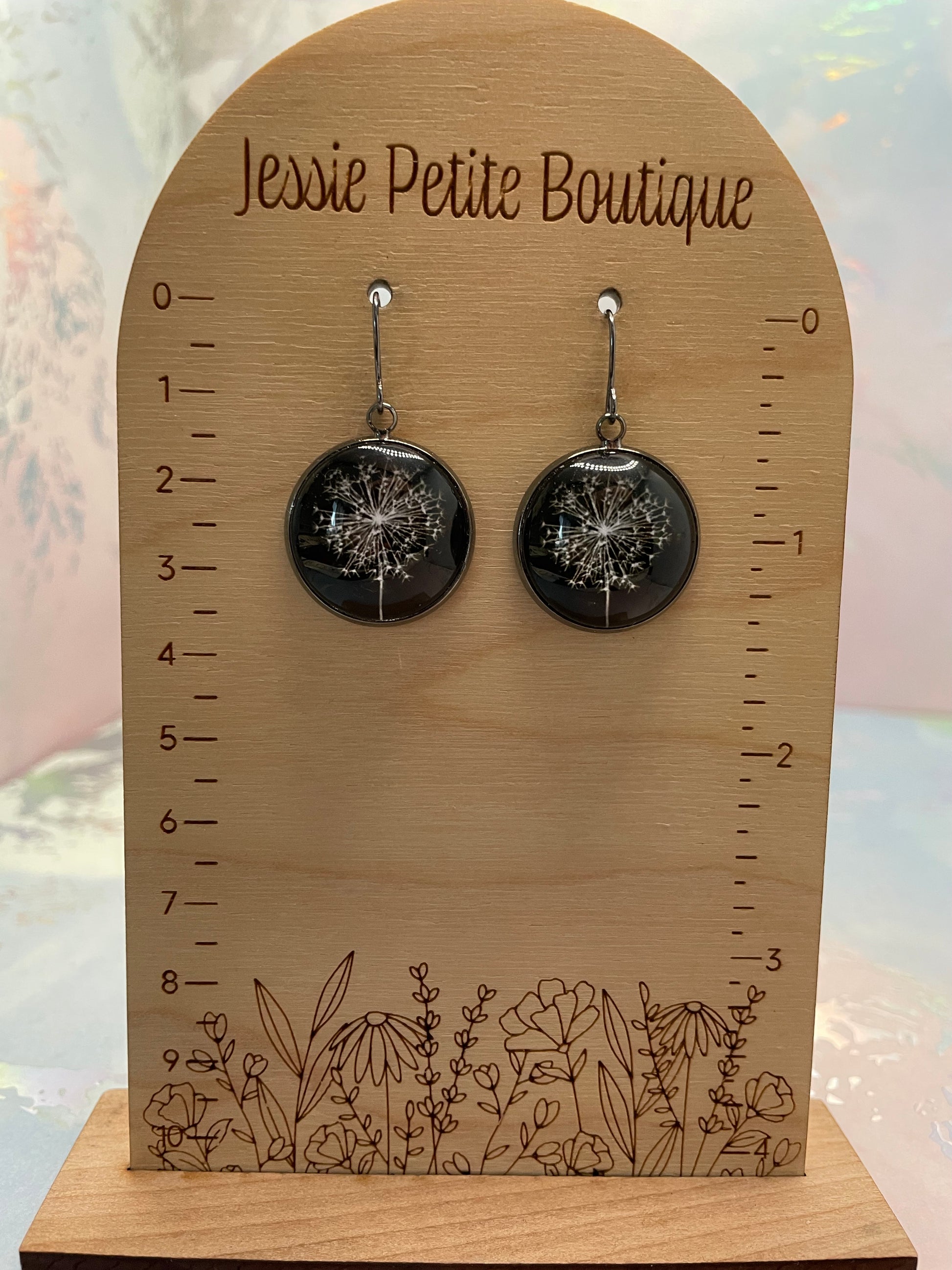 Pair of black earrings on a wooden display card with floral design and 'Jewel Petite Boutique' branding.