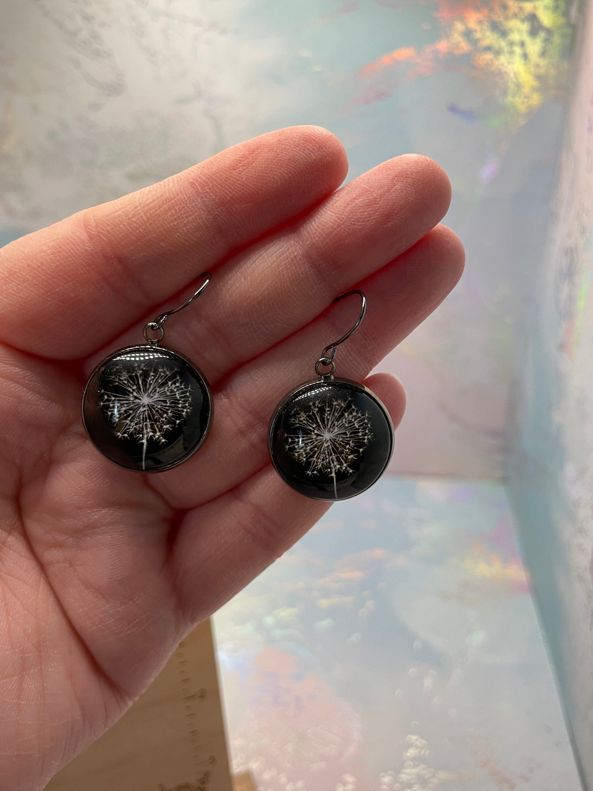 Dandelion Round Cabochon Earrings held in a hand against a blurred background