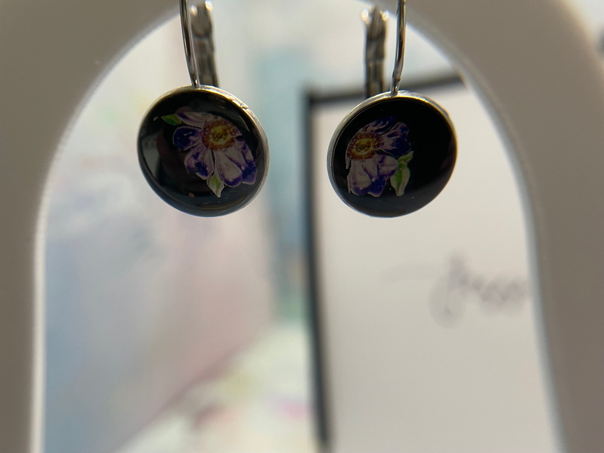 Round earrings with floral design on a blurred background