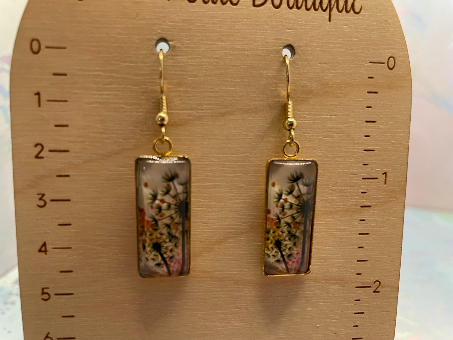 Pair of floral rectangular earrings on a wooden display card with measurement scale.