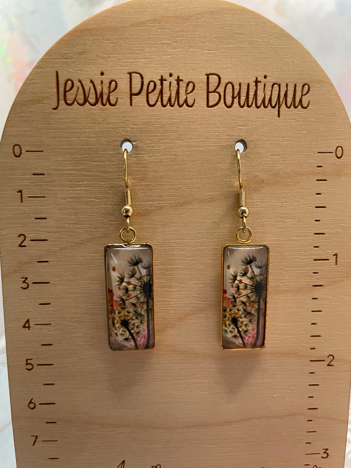 Pair of floral earrings on a wooden display card with 'Jessie Petite Boutique' branding.