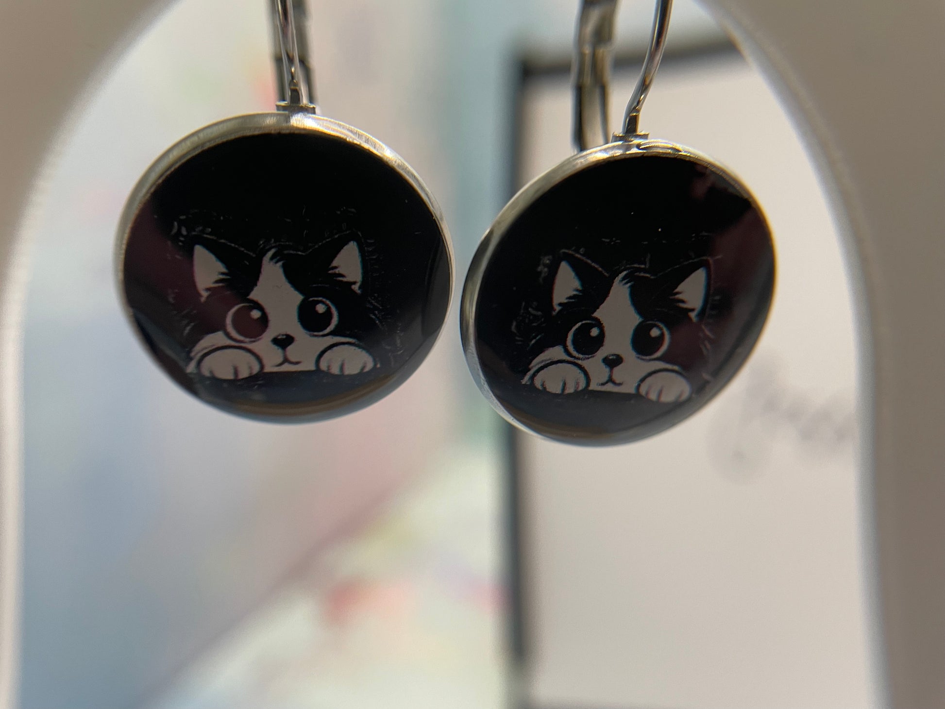 Cat-themed earrings on a blurred background