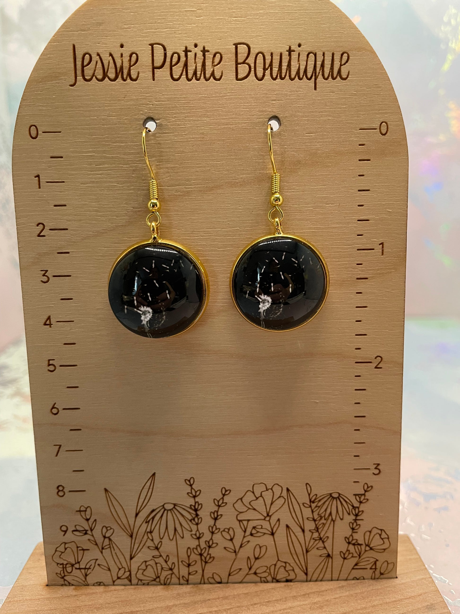 Black floral earrings on a wooden card with 'Jessie Petite Boutique' branding.