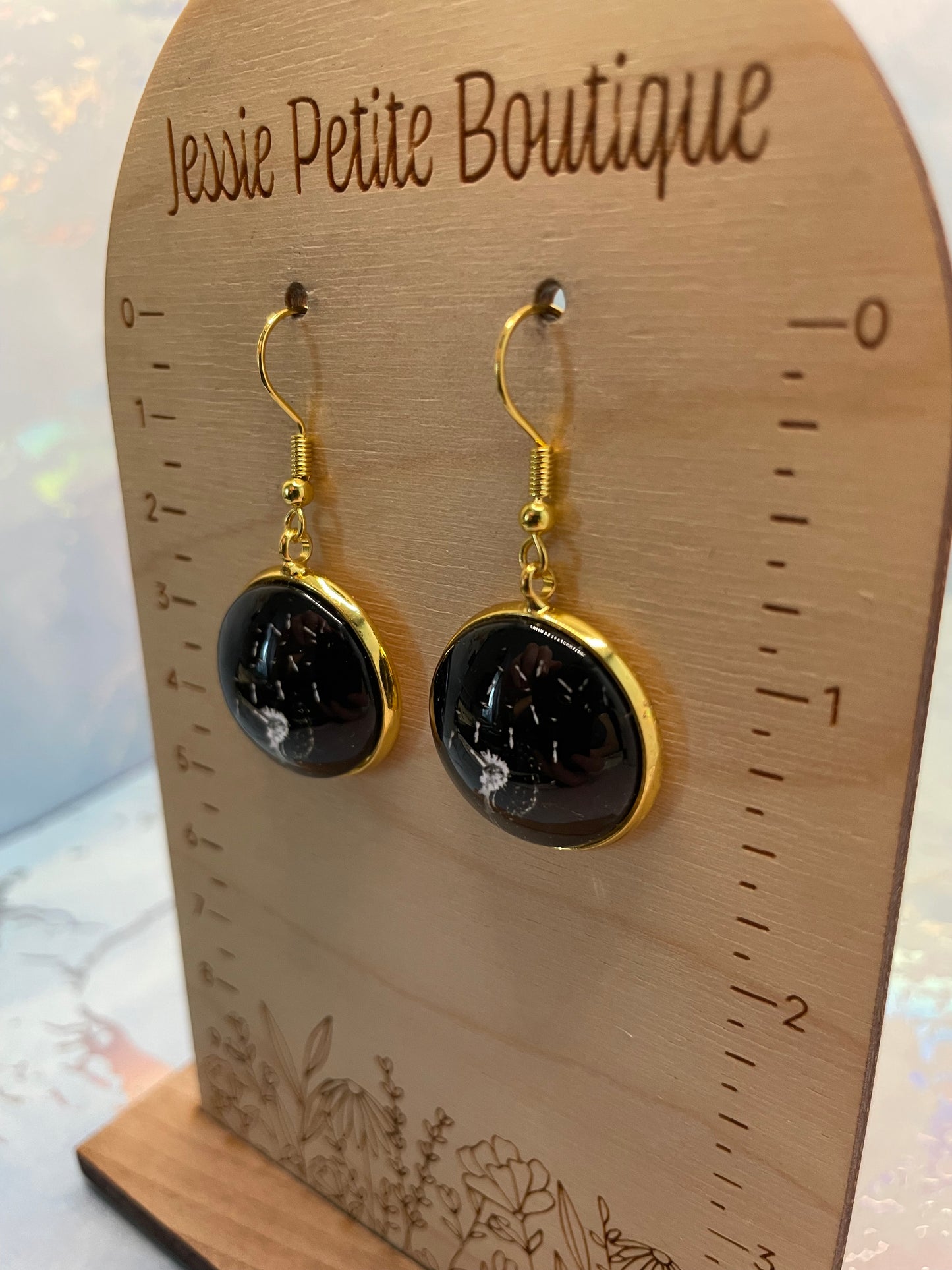 Gold Dandelion Round Cabochon Earrings on a wooden scale from JessIe Petite Boutique.