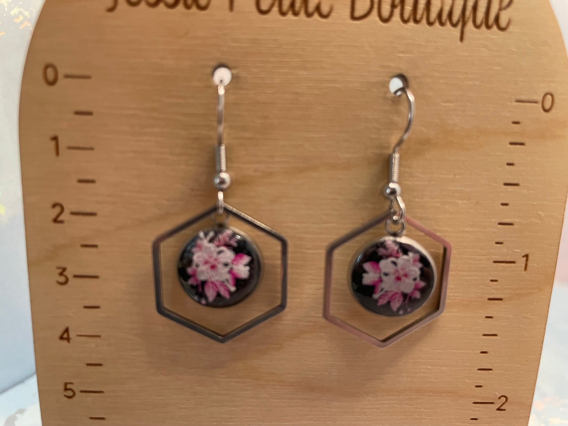 Hexagonal earrings with floral design on a wooden scale
