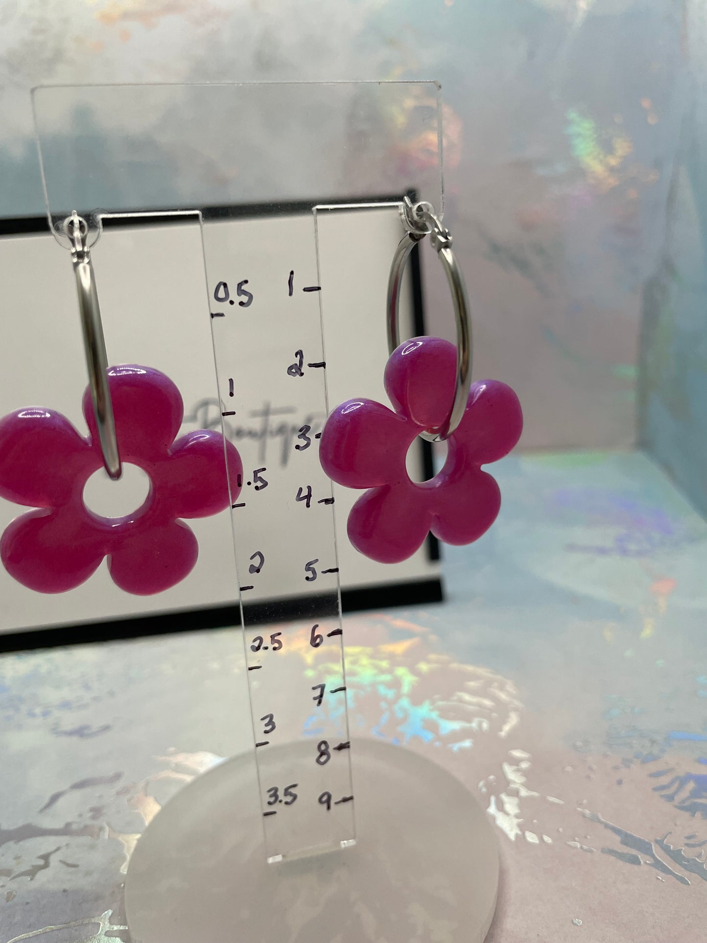 Clear ruler with pink flower-shaped clips on a reflective surface
